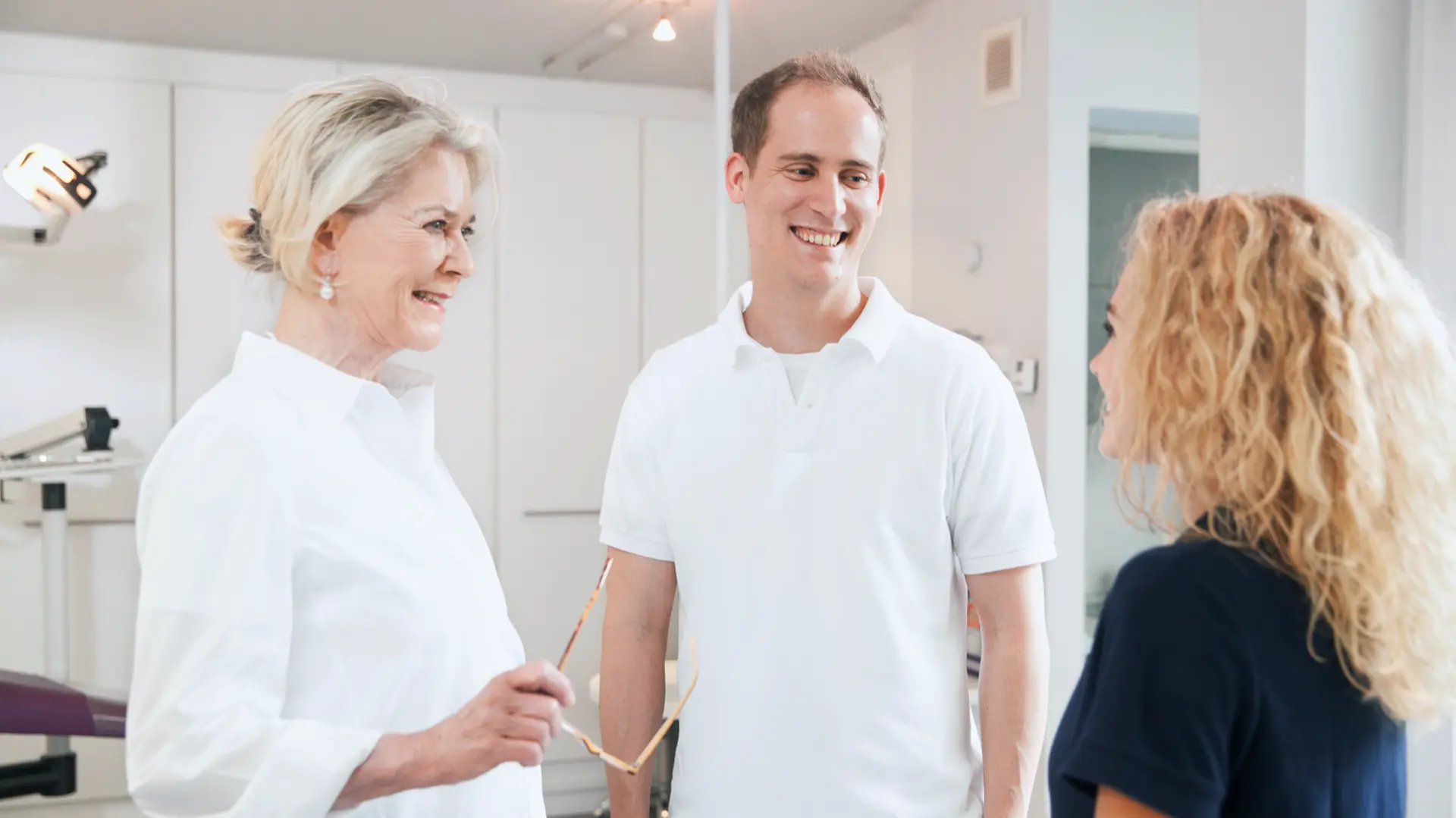Ein Team aus zwei Kieferorthopäden und einer ZFA im Behandlungszimmer